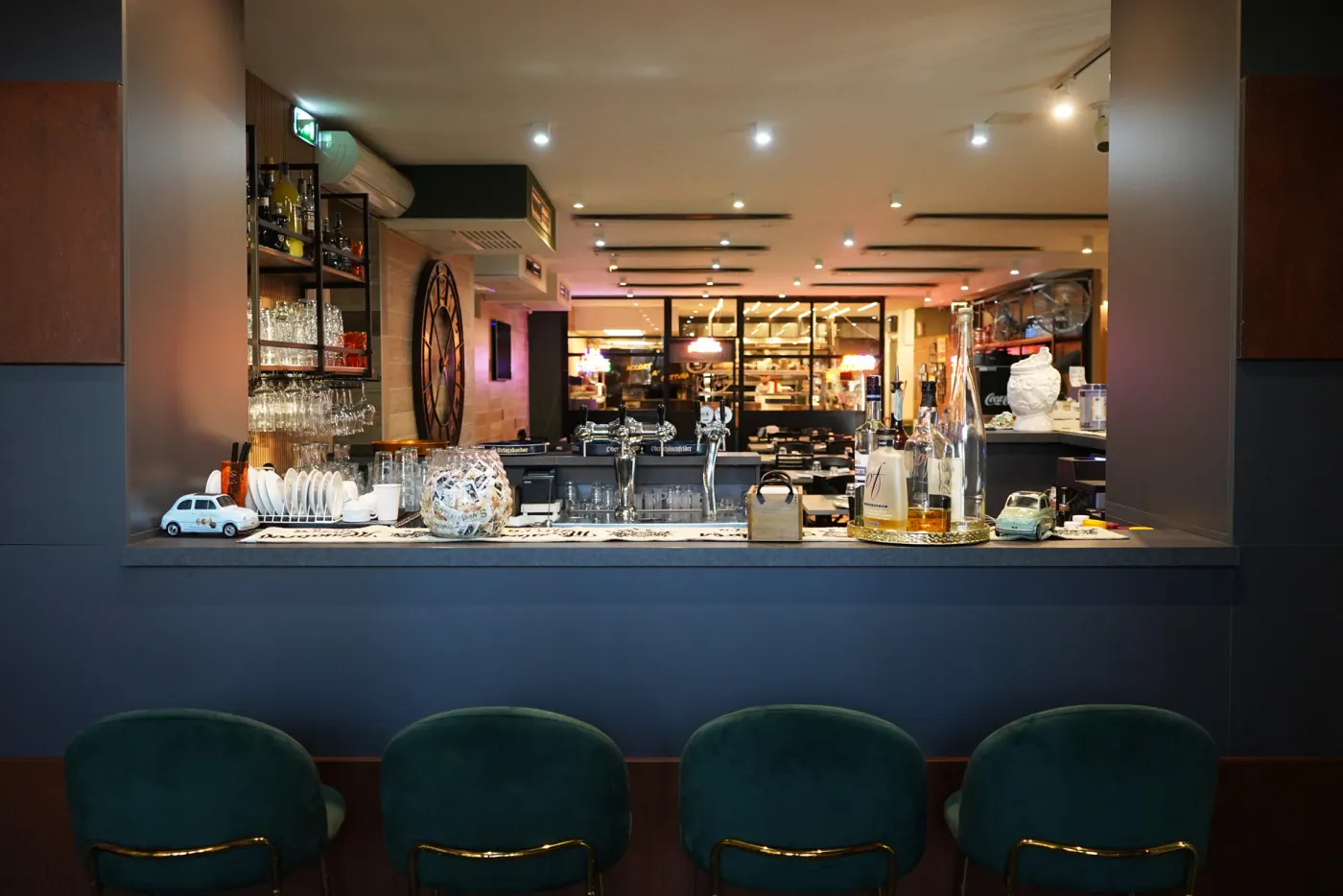 Il bancone del bar con gli sgabelli di velluto verde